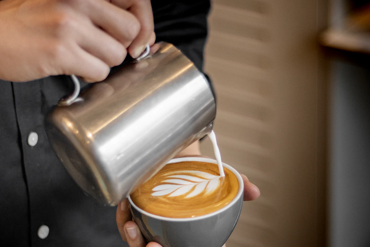 Flat white being poured at a cafe counter